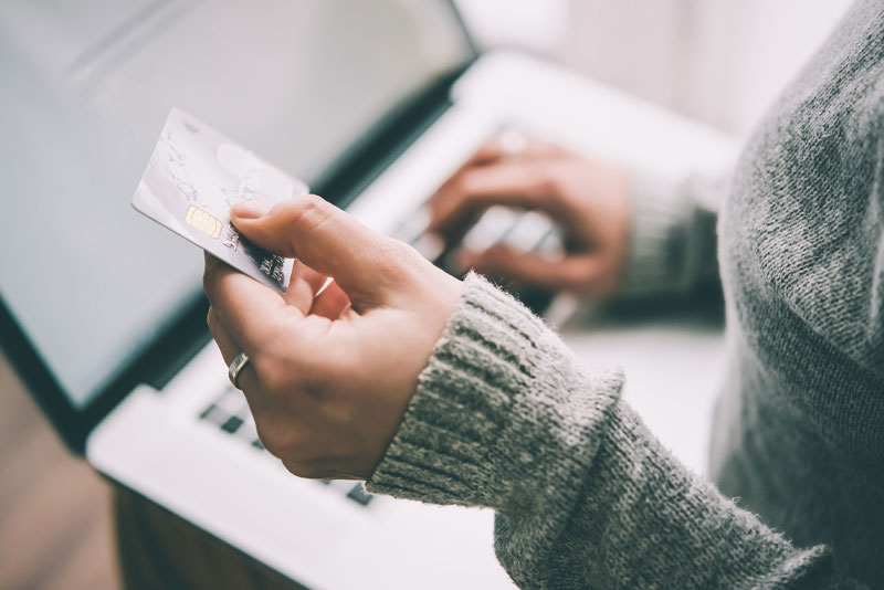 Woman holding credit card and using a laptop