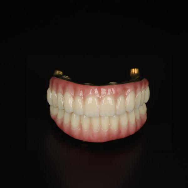A set of upper and lower dentures with pink gums and white teeth displayed against a black background.