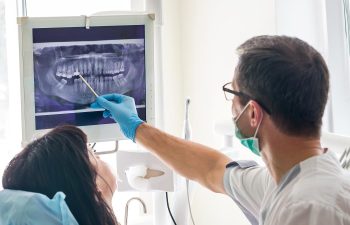 Oral surgeon reviewing a panoramic dental X-ray with a patient during consultation.