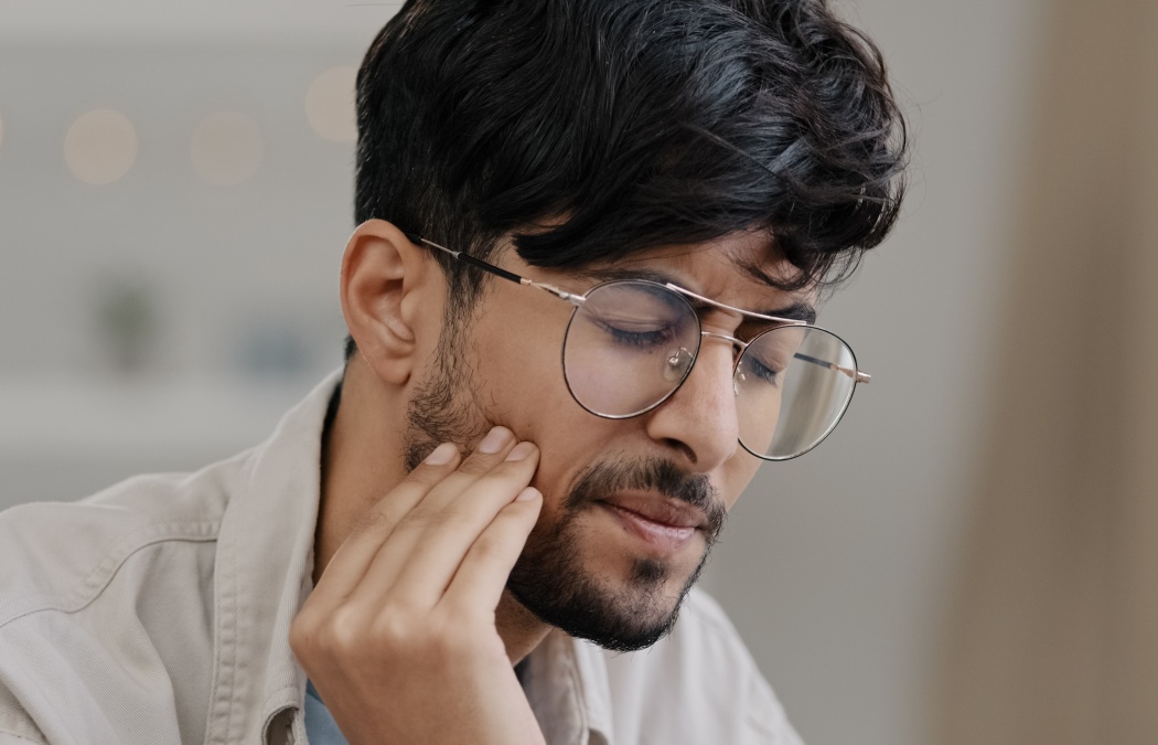 Close-up sick indian man in glasses male sad hispanic arab bearded man suffering tooth pain. Portrait guy feels toothache discomfort in gum caries holdong check with hand dental oral problem concept
